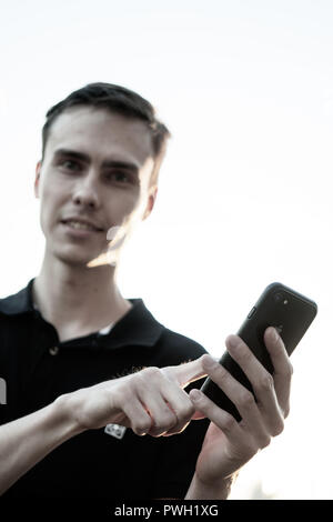 A smartphone is in the hands of a white young man. Stock Photo
