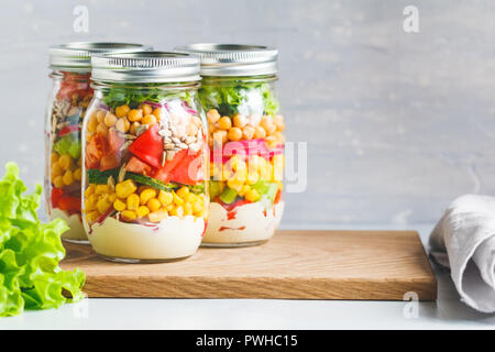 Three glass jars with layering various vegan salads for healthy lunch. Extrem close up. The concept of fitness and vegetarian food. Stock Photo