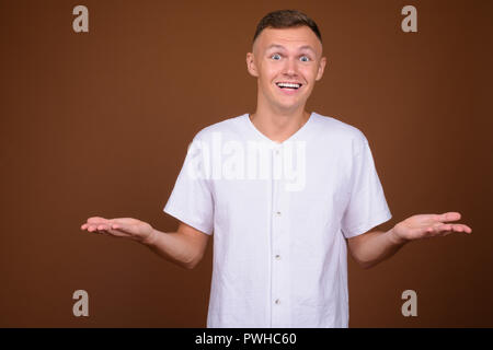 Young man wearing white shirt against brown background Stock Photo