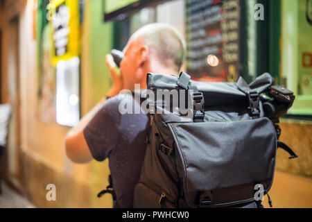 Photographer taking photos of lively streets with restaurants in Alfama, Lisbon, Portugal Stock Photo