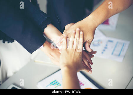 Happy Business people showing team work and giving five after signing agreement or contract with foreign partners in office interior. Stock Photo