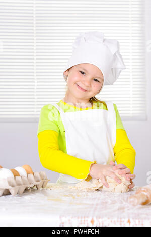 Cute little girl in chef's hat baking cake in the kitchen  Stock Photo