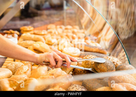 Sales woman in baker shop putting bread roll in paper bag Stock Photo