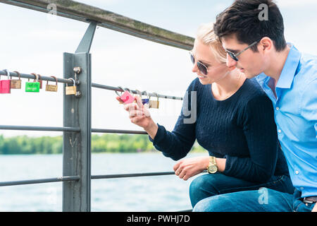 Young couple looking at padlock hang on railing Stock Photo