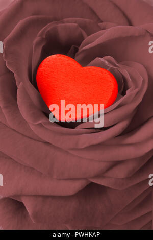 Red heart in a rose flower. Romantic background texture for a Valentine's or Wedding day greetings card, desaturated effect. Stock Photo