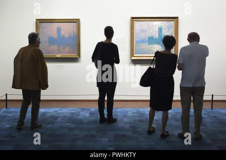 Visitors in front of the paintings by French Impressionist painter Claude Monet from the series 'The Houses of Parliament' displayed at his retrospective exhibition in the Albertina Museum in Vienna, Austria. Paintings 'The Houses of Parliament, Sunset' (1900-1904) and 'The Houses of Parliament, Reflections of the Thames' (1900-1905) are seen in the photo from left to right. The exhibition devoted to the founder of French Impressionist painting runs till 6 January 2019. Stock Photo