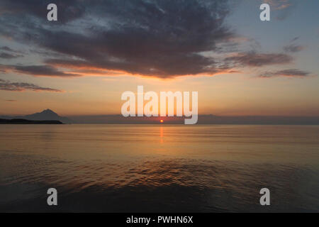 Silhouette of mount Athos at sunrise or sunset with light rays and sea panorama in Greece Stock Photo