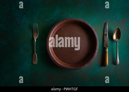 Ceramic tableware pottery plate on grunge green background vintage cutlery Stock Photo