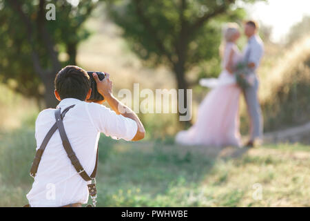 wedding photographer takes pictures of bride and groom Stock Photo