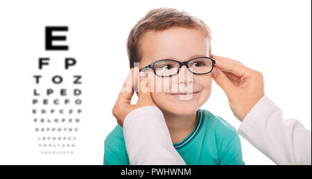 Little boy testing new eyeglasses, optician is adjusting new frame glasses on child's face. Stock Photo