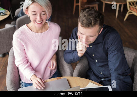 Two coworkers working together on laptop. Pretty experienced woman explaining her inferior how to use computer programm. Stock Photo