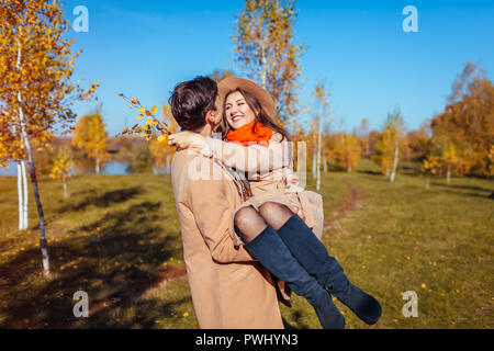 Young couple walks in autumn forest. Man carrying his girlfriend in hands and laughing. Romantic date Stock Photo