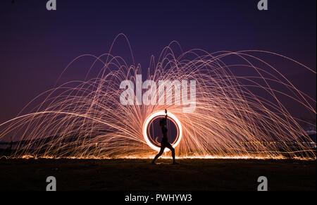 Silhouette Asia woman yoga on the beach at sunset with Steel wool spinning background Stock Photo