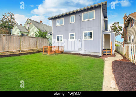 Blue home exterior with large fully fenced back yard and well kept lawn. Stock Photo