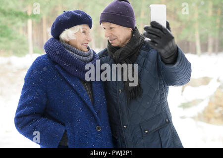 Senior Couple Taking Selfie in Winter Forest Stock Photo