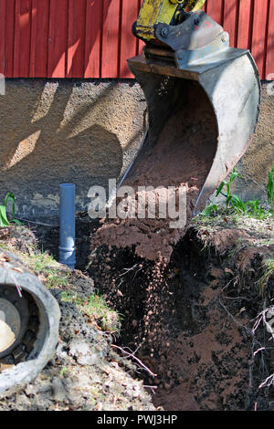 Excavator in construction site filling the sewer pipe trench with sand. Vertical image. Stock Photo