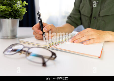 Woman's hands with pen writing on notebook. Modern office desk. Working, writing concept Stock Photo