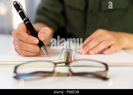 Woman's hands with pen writing on notebook. Modern office desk. Working, writing concept Stock Photo