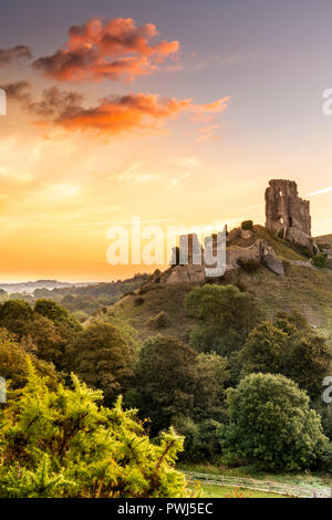 After another cold night, a colourful sunrise over the historic ruins of Corfe Castle heralds the start to rising temperatures in the county of Dorset Stock Photo