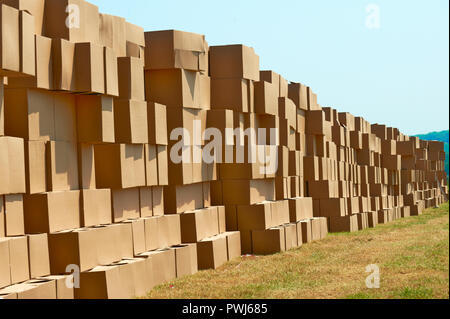 Stacked cardboard boxes outdoors in long row Stock Photo