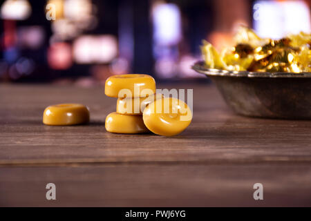 Group of five whole caramel cream candy butterscotch variety in old iron bowl with restaurant in background Stock Photo