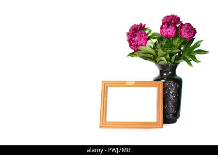 Beautiful lilac peonies in vase and wooden frame on white isolated background. Stock Photo