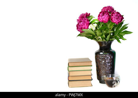 Beautiful lilac peonies in a vase, a Cup of tea and a book on a white isolated background. Stock Photo