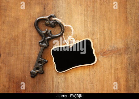 Image of antique key and empty blackboard tag over old wooden table Stock Photo