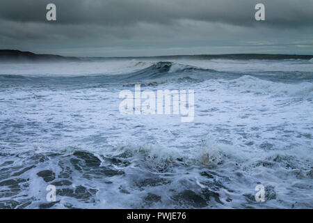 huge white capped waves rolling in from the atlantic ocean under a storm cloud filled sky. Stock Photo