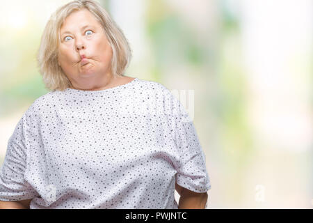 Senior plus size caucasian woman over isolated background making fish face with lips, crazy and comical gesture. Funny expression. Stock Photo