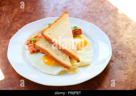 scrambled eggs with beans and toast on a white plate Stock Photo