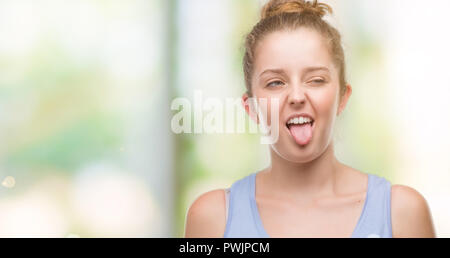 Young blonde woman sticking tongue out happy with funny expression. Emotion concept. Stock Photo