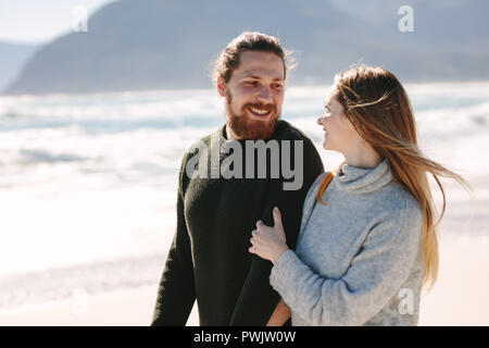Handsome man walking with his girlfriend at the beach. Young couple together along the sea shore. Stock Photo