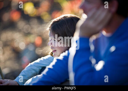 Smiling young girl sitting next to her father outdoors. Stock Photo