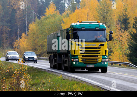 Salo, Finland - October 13, 2018: Yellow and green Scania R500 truck hauls a load of sugar beet on rural highway in Finland flanked by autumn foliage. Stock Photo