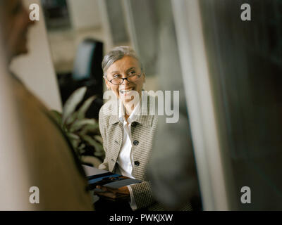 Secretary laughing with her co-worker. Stock Photo