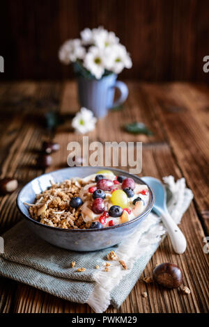 Granola with yogurt, grapes, blueberries, coconut chips and chestnut puree in a bowl Stock Photo