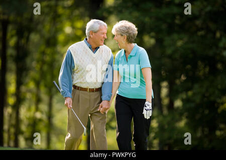 Older couple laughing on golf course Stock Photo