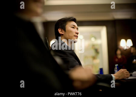 Young adult businessman listening in a boardroom. Stock Photo