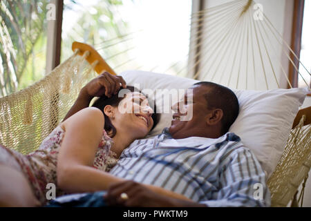 Mid-adult couple cuddling in a hammock. Stock Photo