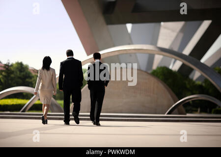 Three business colleagues walking side by side through a courtyard. Stock Photo