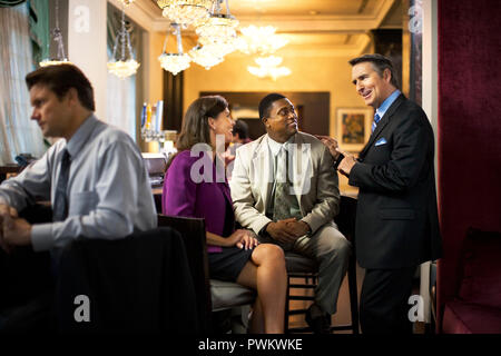 Smiling group of co-workers enjoy themselves as they relax and chat together at a classy bar after work. Stock Photo