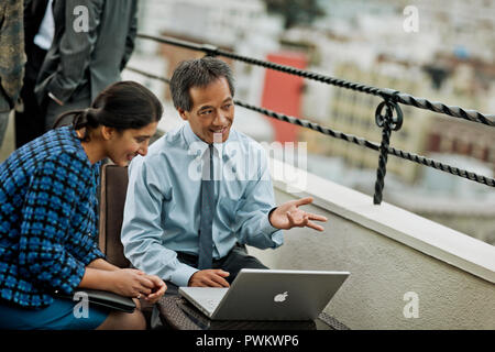 Mature businessman demonstrates something on a laptop to a young colleague during an outdoor meeting. Stock Photo