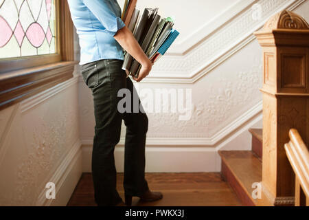 Woman holding stack of files on staircase Stock Photo