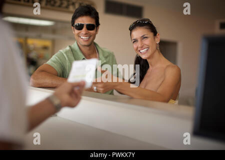Happy young couple check in at an airport check in counter. Stock Photo