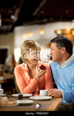 Affectionate mature couple enjoy eating breakfast together at a cafe.