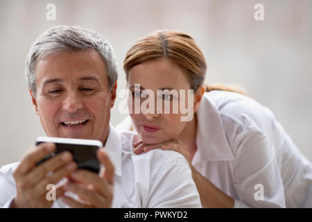 Professional couple looking at something on an iphone. Stock Photo