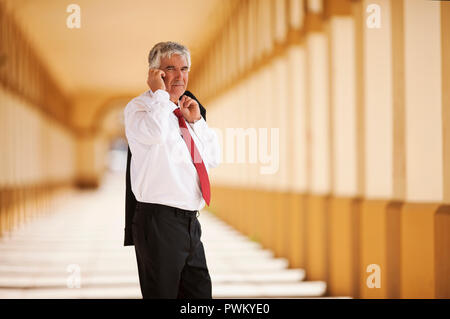 Senior businessman talking on cell phone in train station. Stock Photo