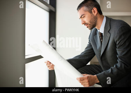 Businessman looks at building plans. Stock Photo