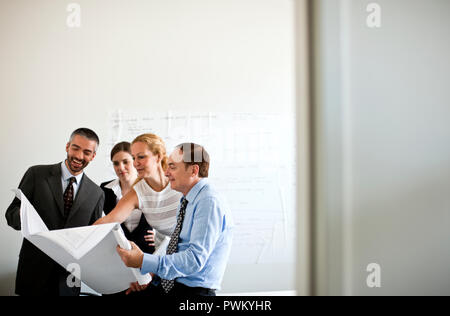 Small group of business people in a meeting looking at business plans. Stock Photo